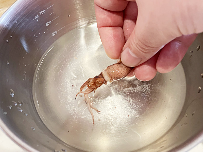 処理したホタルイカを塩水で洗う